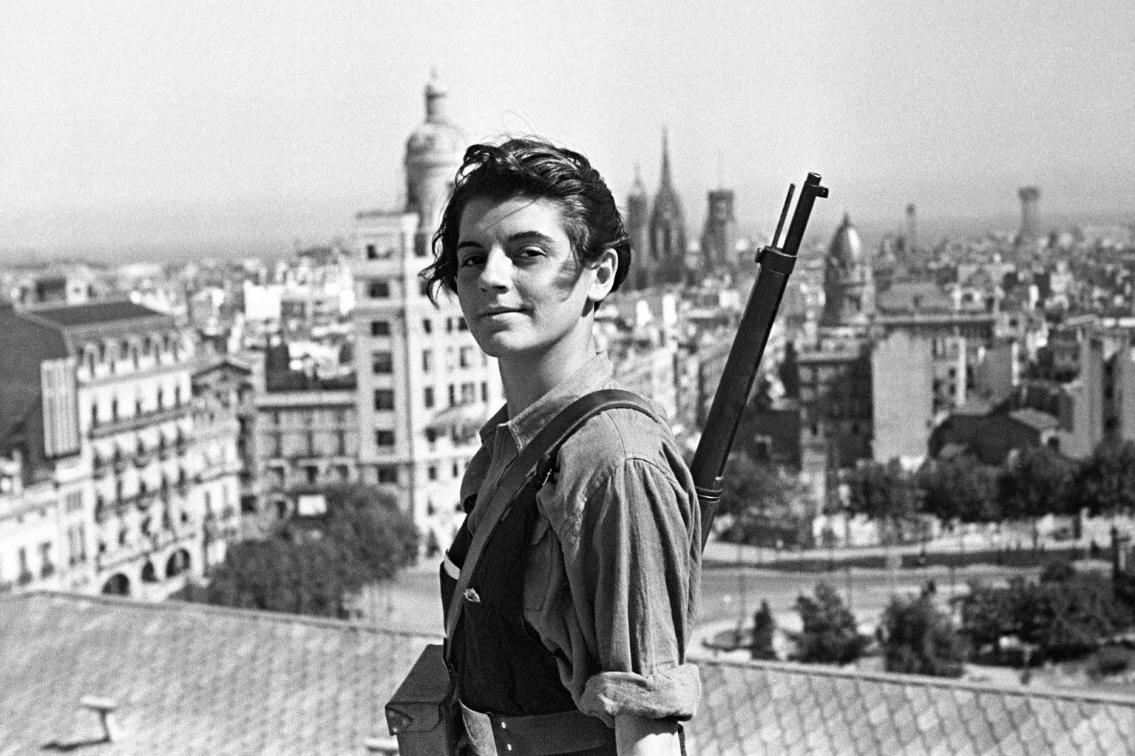 A girl on a roof faces the camera confidently, a rifle slung over her shoulder, with a city behind her.