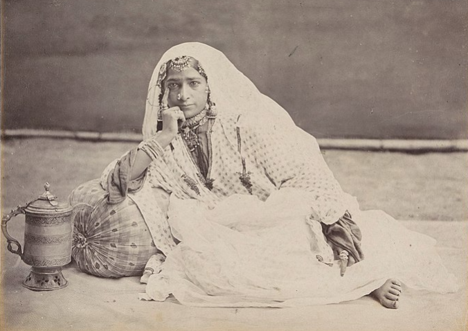 A young Indian woman wearing traditional clothing rests while propping her head with her hand.